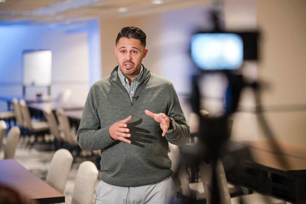 A speaker being interviewed on camera in a Denver conference room during a DHC Media shoot.