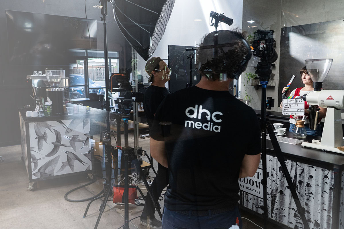 A DHC Media crew filming an interview on location in a Denver coffee roastery